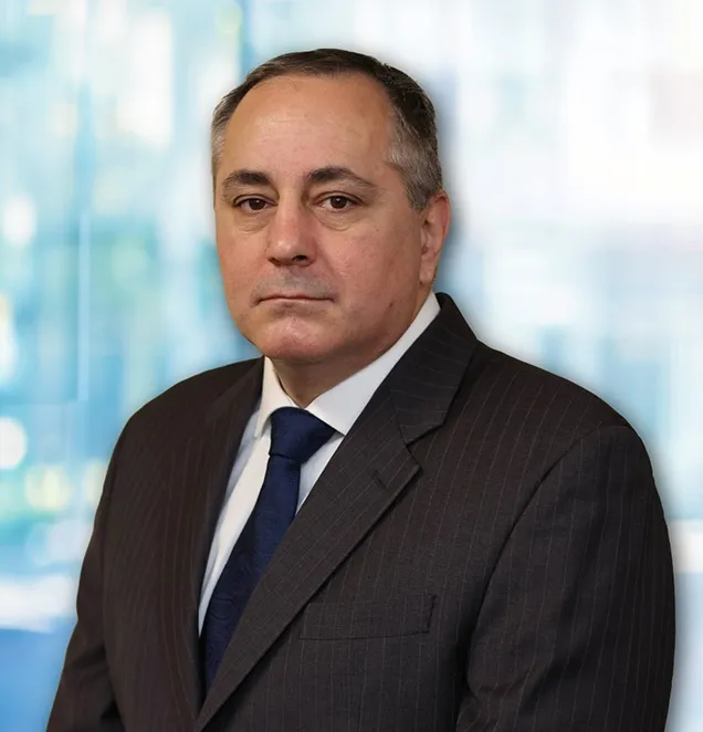 Professional headshot of middle-aged man in dark suit and blue tie