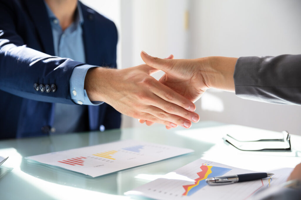 Elevated View Of Businessman Shaking Hands With His Partner Over Desk