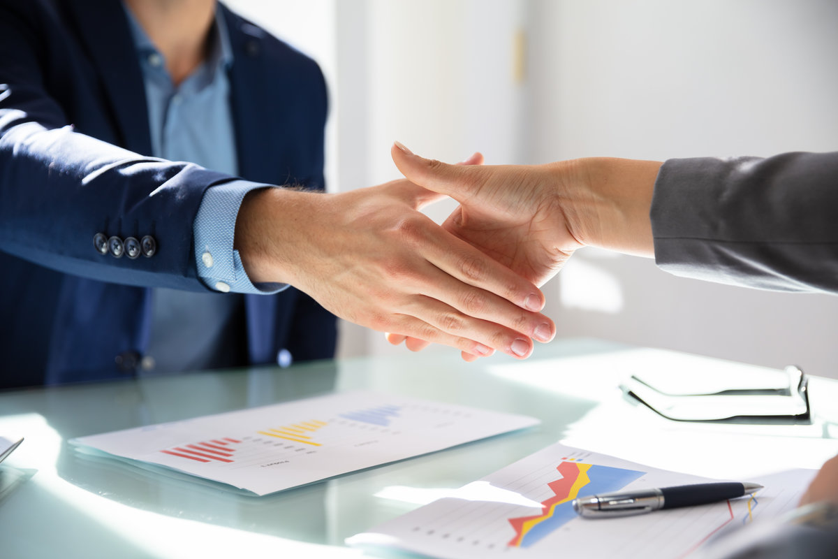 Elevated View Of Businessman Shaking Hands With His Partner Over Desk