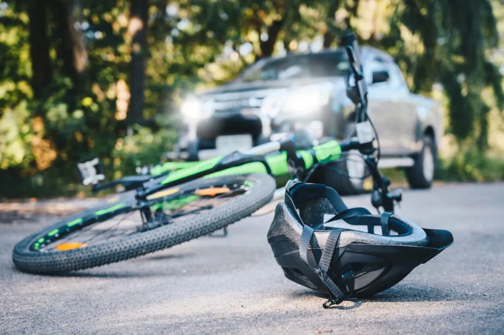 Close-up of a bicycling helmet fallen on the asphalt next to a bicycle after car accident on the road. Conceptual of accident car crash with bicycle on road.