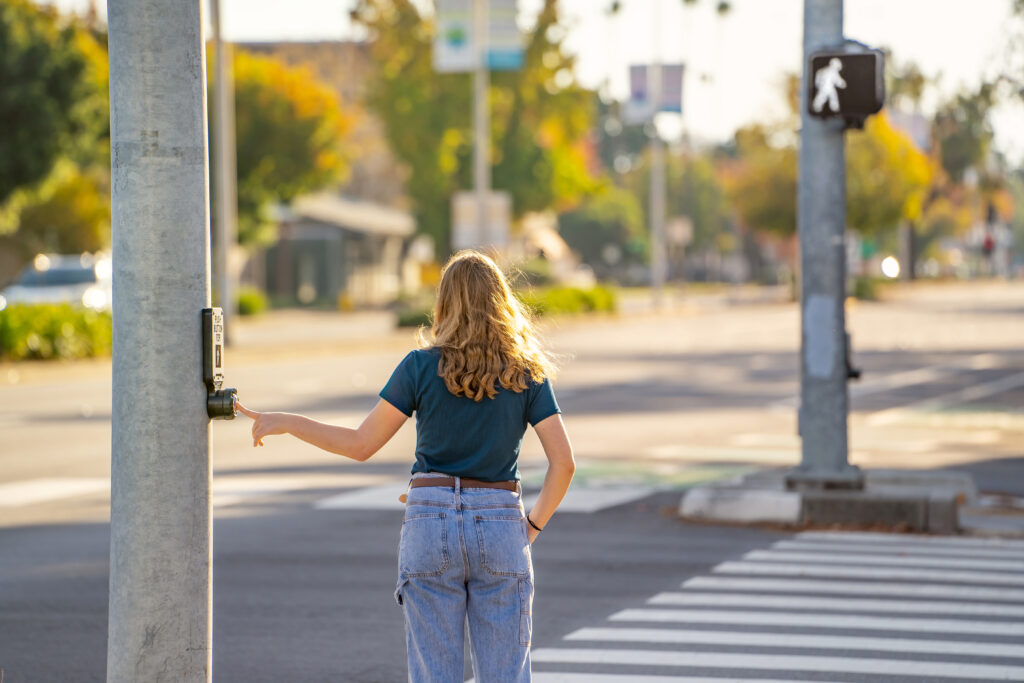 A young woman pressing the button to cross the road.