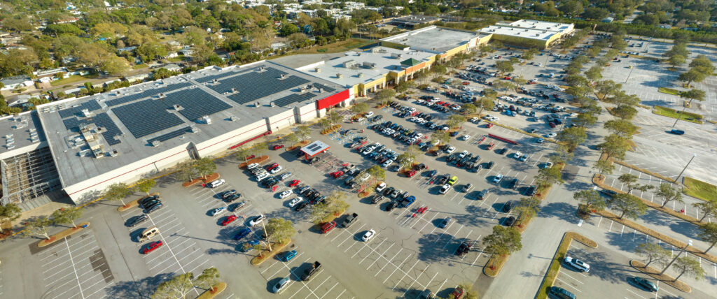 Large parking lot with many parked cars. Big carpark at supercenter shopping mall with lines and markings for vehicle places and directions.