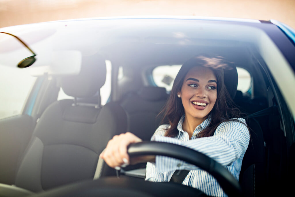 Happy woman driving a car and smiling. Cute young success happy