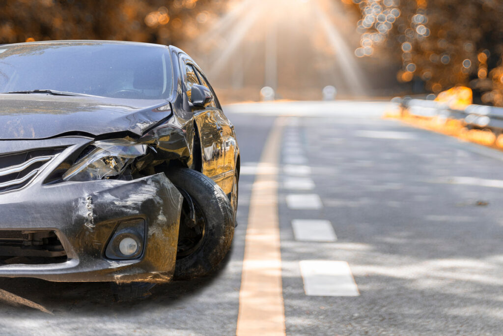 Artumn road. Front of black color car big damaged and broken by accident on road parking can not drive any more. With copy space for text or design