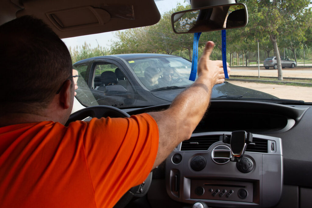 Furious man gesticulates with hand while driving. Crazy driver yelling from car. Stress, traffic rush, anxious, madness, rudeness