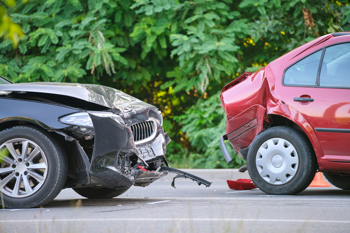 Damaged in heavy car accident vehicles after collision on city street crash site. Road safety and insurance concept