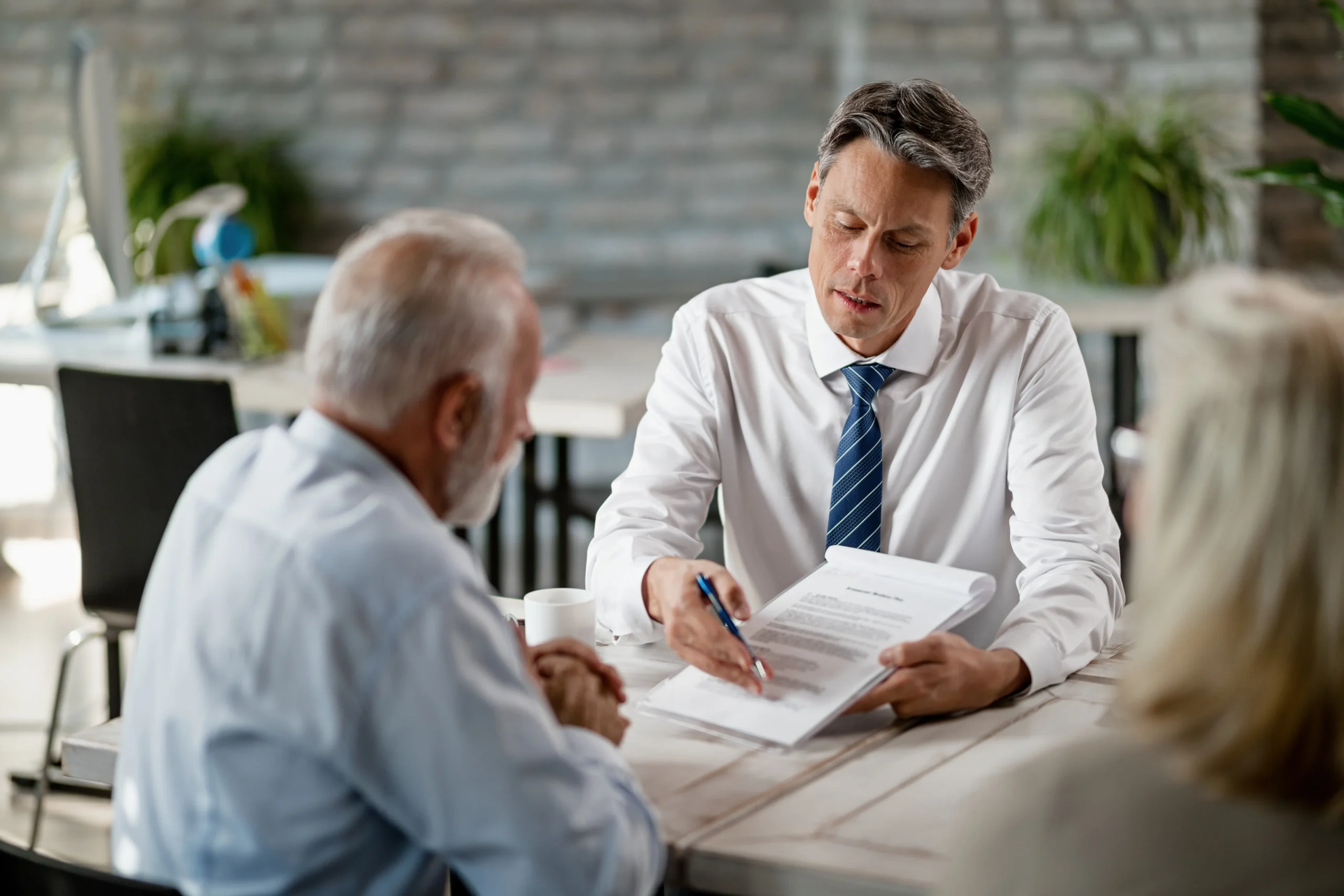 Insurance agent meeting with senior couple to review contract terms in an office