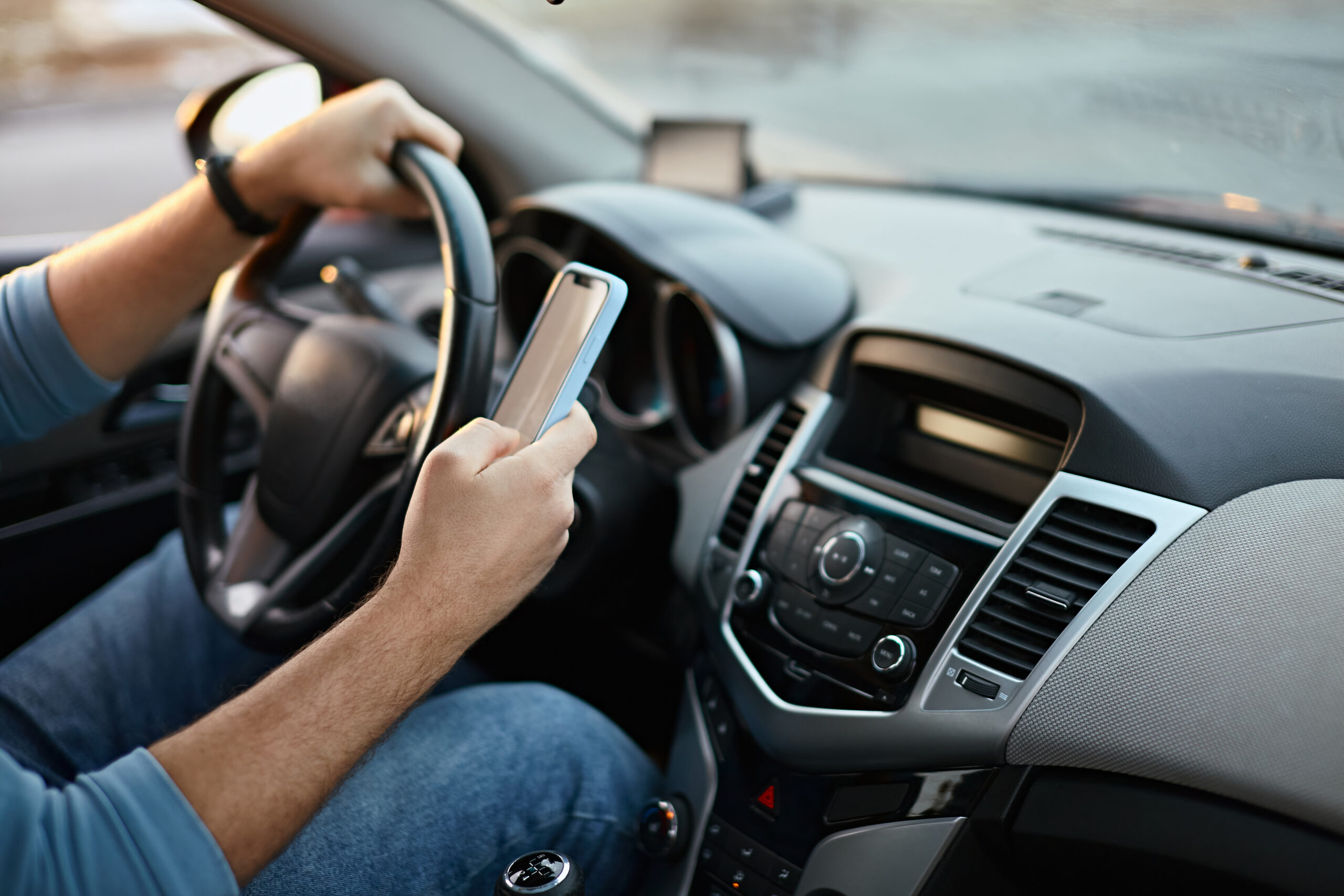 Driver's hands on steering wheel while using a mobile phone while driving