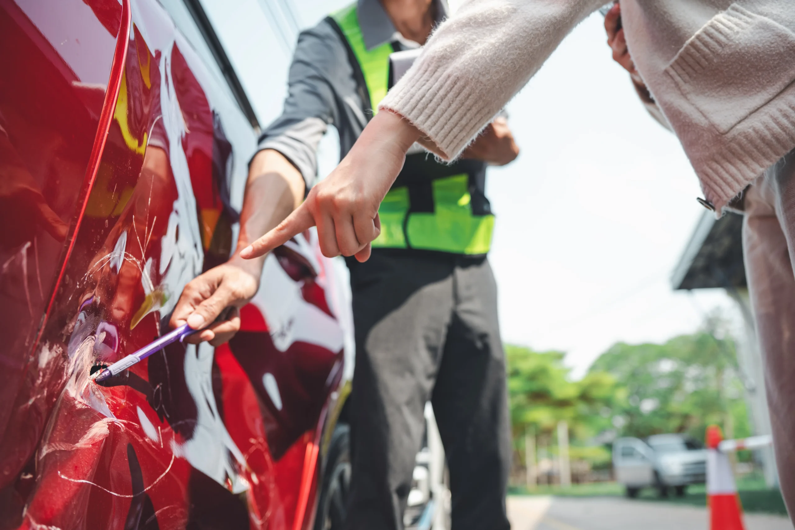 Insurance agent inspecting car damage and pointing out impact marks after an accident
