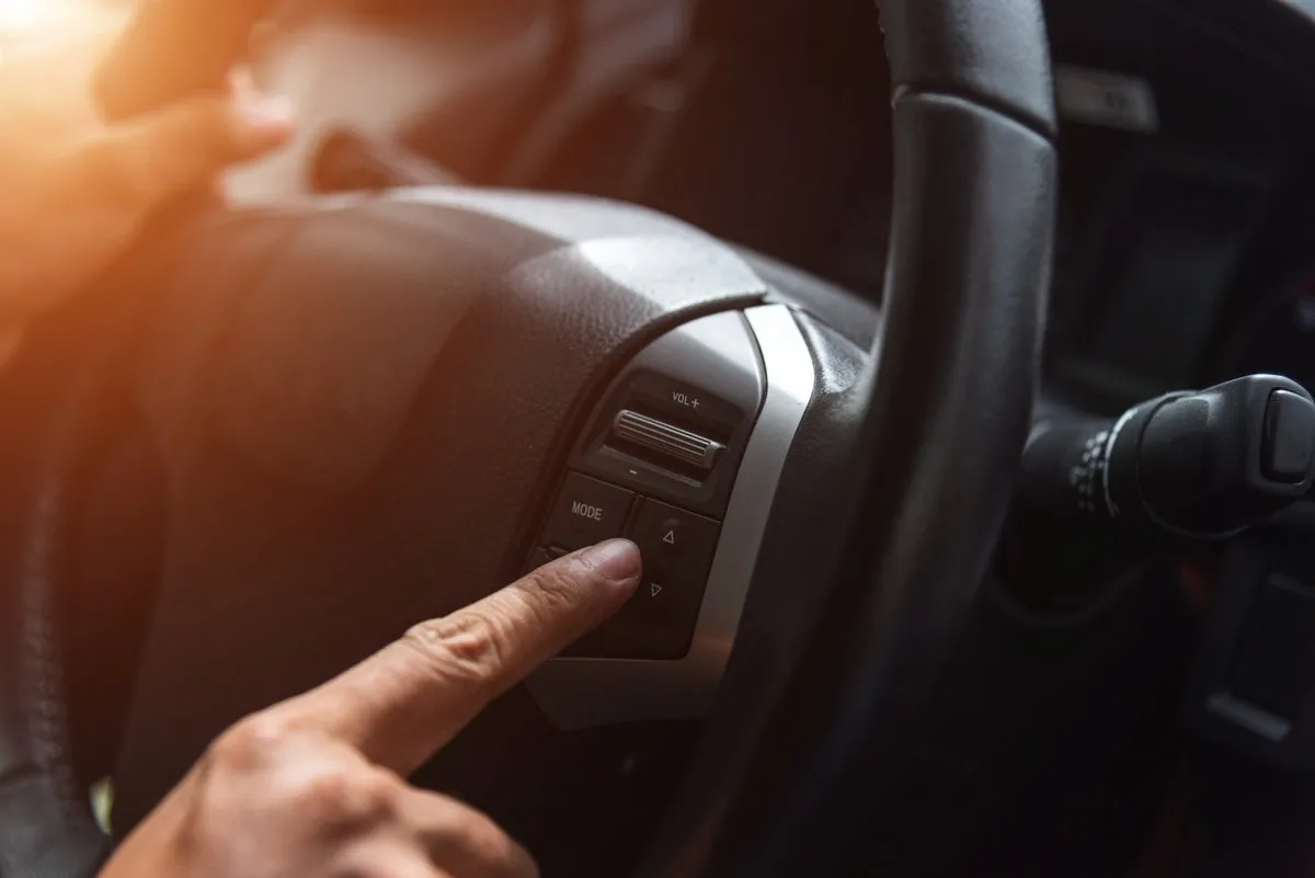 Hand tuning fm radio button in car panel.