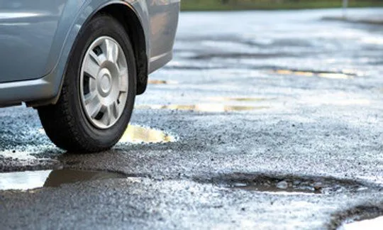 Damaged road with pothole illustrating road design defects and government liability